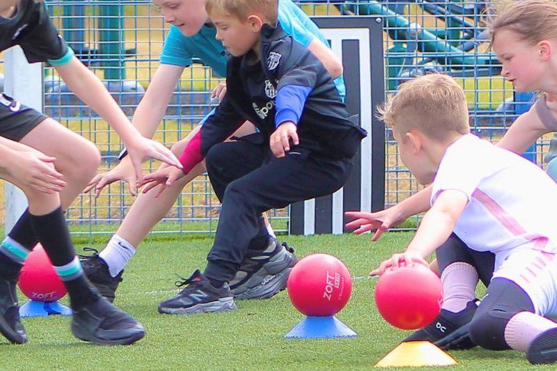 Children using foam dodgeballs to play a game on a 2026 school asto-turf field